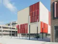 Moderne Gebäude der Hochschule Essen mit hellen Ziegelwänden und auffälligen roten Fassadenelementen.