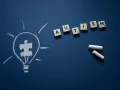 Żarówka z symbolem puzzli i litery tworzące słowo AUTISM. Wiele sławnych osób z autyzmem inspiruje nas każdego dnia.