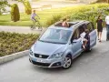 Familienauto mit zwei Kindern, die ein- und aussteigen. Ein Junge fährt Fahrrad im Hintergrund.