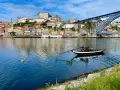 A traditional Rabelo boat with barrels, a symbol of Porto's wine heritage, floats on the Douro River. This iconic view is a must-see for any Porto travel guide.