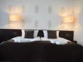 Przytulny pokój hotelowy z podwójnym łóżkiem, białymi ręcznikami i lampami. Czy można wynająć pokój w hotelu mając 17 lat?