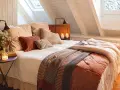 Dormitorios cálidos y acogedores bajo un techo abuhardillado. Cama con mantas de punto y cojines mullidos. Velas y flores crean un ambiente íntimo.