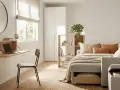 Habitación de invitados y estudio con escritorio plegable, sofá cama y estantería.