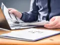 Osoba przegląda dokumenty przy laptopie. Na pierwszym planie folder z symbolem wagi, sugerujący sprawy związane z prawem i potencjalną masą upadłościową.
