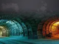 Wnętrze kopalni Nowa Ruda. Tunel oświetlony niebieskim i pomarańczowym światłem, z drewnianymi podporami i torami kolejowymi.