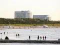 Ludzie spacerują po najszerszej plaży w Polsce, w tle hotele Radisson i Hilton.