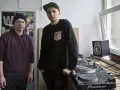 Dwóch mężczyzn przy sprzęcie DJ-skim. Jeden w bordowej bluzie z kapturem, drugi w czarnej bluzie z naszywką. To ich sposób na pokazanie, co to stereo.