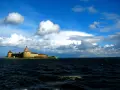Forteca na wyspie nad największym jeziorem Europy, woda faluje pod błękitnym niebem z chmurami.