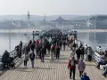 Tłumy ludzi spacerują po drewnianym molo w Sopocie. Czy molo w Sopocie jest płatne? Tego dnia wejście było darmowe, co przyciągnęło wielu turystów.
