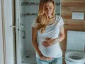 Kobieta w ciąży z bólem brzucha, która musi skorzystać z toalety. Kichanie w ciąży bywa uciążliwe.