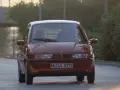 Pomarańczowy BMW E1 jedzie po drodze, światła odbijają się od karoserii.