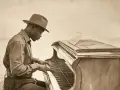Ein Mann mit Hut spielt Klavier. Seine Finger tanzen über die Tasten, als würde er die Essenz von "was ist Jazz" einfangen.