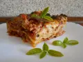 Kawałek pysznej lasagne z mięsem mielonym, udekorowany listkami bazylii. Prosty przepis na domową lasagne.