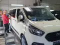 Mann foliert einen weißen Transporter, um die **Taxi Umbau Kosten** zu optimieren.