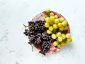Zwei Trauben, dunkle und helle, liegen auf einem Teller. Sie sind ein Beweis dafür, wie gesund weintrauben sind.
