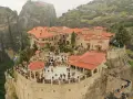 A stunning view of the monasteries of Meteora, perched atop towering rock formations. Visitors explore the courtyards and pathways, a testament to the enduring spirit of this sacred place.