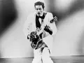 Chuck Berry in weißem Anzug spielt Gitarre, bereit für "Johnny B. Goode".