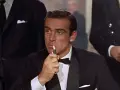 James Bond, elegante in smoking, accende una sigaretta con un'aria pensierosa.