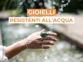 Mano adornata con gioielli che non si rovinano con l'acqua, sotto un getto d'acqua scintillante.