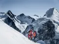 Zwei Bergsteiger, ein beal escaper-Team, steigen einen schneebedeckten Hang hinauf, umgeben von majestätischen, eisigen Gipfeln.