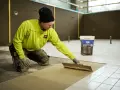 Man i gul jacka lägger fix på golvet för att byta ut det.