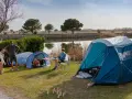 Przyjemny dzień na polu namiotowym nad jeziorem. Ludzie relaksują się, grają w gry i cieszą się naturą.