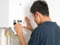Tecnico effettua il collaudo caldaia nuova, regolando i comandi per un funzionamento ottimale.