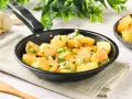 Patatas al ajillo recién hechas en sartén, con perejil fresco y ajos picados. ¡Un plato sencillo y delicioso!