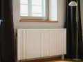Radiateur électrique blanc moderne près d'une fenêtre. Idéal pour bénéficier de l'aide de l'état pour changer radiateur électrique.
