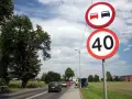 Znaki drogowe: zakaz wyprzedzania i ograniczenie prędkości do 40 km/h. Droga z samochodami i drzewami.