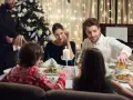 Rodzina celebruje święta w hotelu. Kelner nalewa napój, a przy stole panuje świąteczna atmosfera.