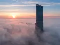 Sky Tower Wrocław, jego imponująca wysokość ginie we mgle o wschodzie słońca. Widok zapiera dech.