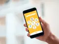 Mano sujetando un smartphone con una app de entregas. Muestra opciones como "Comida", "Supermercado" y "Parafarmacia". Así funciona "just eat".