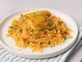 Arroz con pollo jugoso con verduras y perejil picado en un plato blanco.