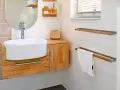 Meuble de salle de bain en bois clair, avec vasque blanche et robinetterie moderne. La hauteur du meuble est idéale pour un accès facile.
