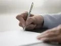 Dłoń testamentora pisze długopisem na dokumencie.