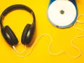 Kopfhörer und ein Discman auf gelbem Hintergrund. Perfekt, um neue Musik zu promoten und den Sound zu genießen.