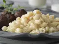 En tallrik med stuvade makaroner och köttbullar, garnerat med en kvist örter. En klassisk svensk rätt som värmer själen.