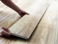 Man's hands placing a laminate plank to repair suelo laminado.