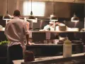 Kucharz w białej koszuli i fartuchu pracuje w kuchni restauracyjnej. To idealne miejsce, by napisać list motywacyjny kucharz.
