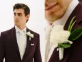 Elegancki mężczyzna w garniturze w kolorze bordowym, z kremowym krawatem i butonierką z białych róż.