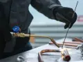 Ręce w rękawicach wykonują lutowanie twarde miedzianych rur palnikiem.