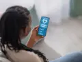Kobieta sprawdza na telefonie swoje skoki tętna i aktywność fizyczną. Widzi 68 uderzeń na minutę, spalone kalorie i pokonane kroki.