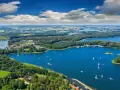 Malownicze, klimatyczne miejsca nad jeziorem, gdzie lasy schodzą do wody, a żaglówki unoszą się na błękitnej tafli.