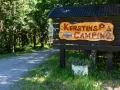 Välkommen till Kerstins Camping! En skylt i trä visar vägen till en lugn plats i skogen.