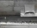 Izolowane rury wentylacyjne z okrągłym nawiewnikiem pod betonowym sufitem.