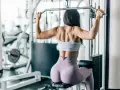 Kobieta wykonuje trening góra dół na maszynie typu ściąganie drążka wyciągu górnego.