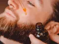 Un hombre aplica aceite con un gotero a su barba. Un secreto para tener una barba bonita y cuidada.