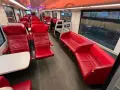 Interior of a modern train, with red leather seats and tables, ready for a journey from AMS to Brussels.