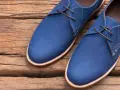 Un paio di eleganti scarpe blu con lacci marroni, perfette per completare un abito blu.